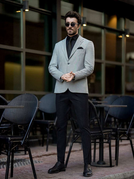 Man wearing XAYWEAR two piece suit for men with grey blazer and black pants standing outdoors