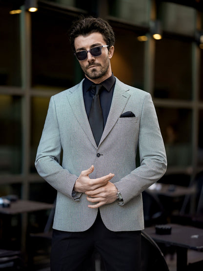 Man wearing XAYWEAR gray two piece suit for men with black shirt and tie outdoors
