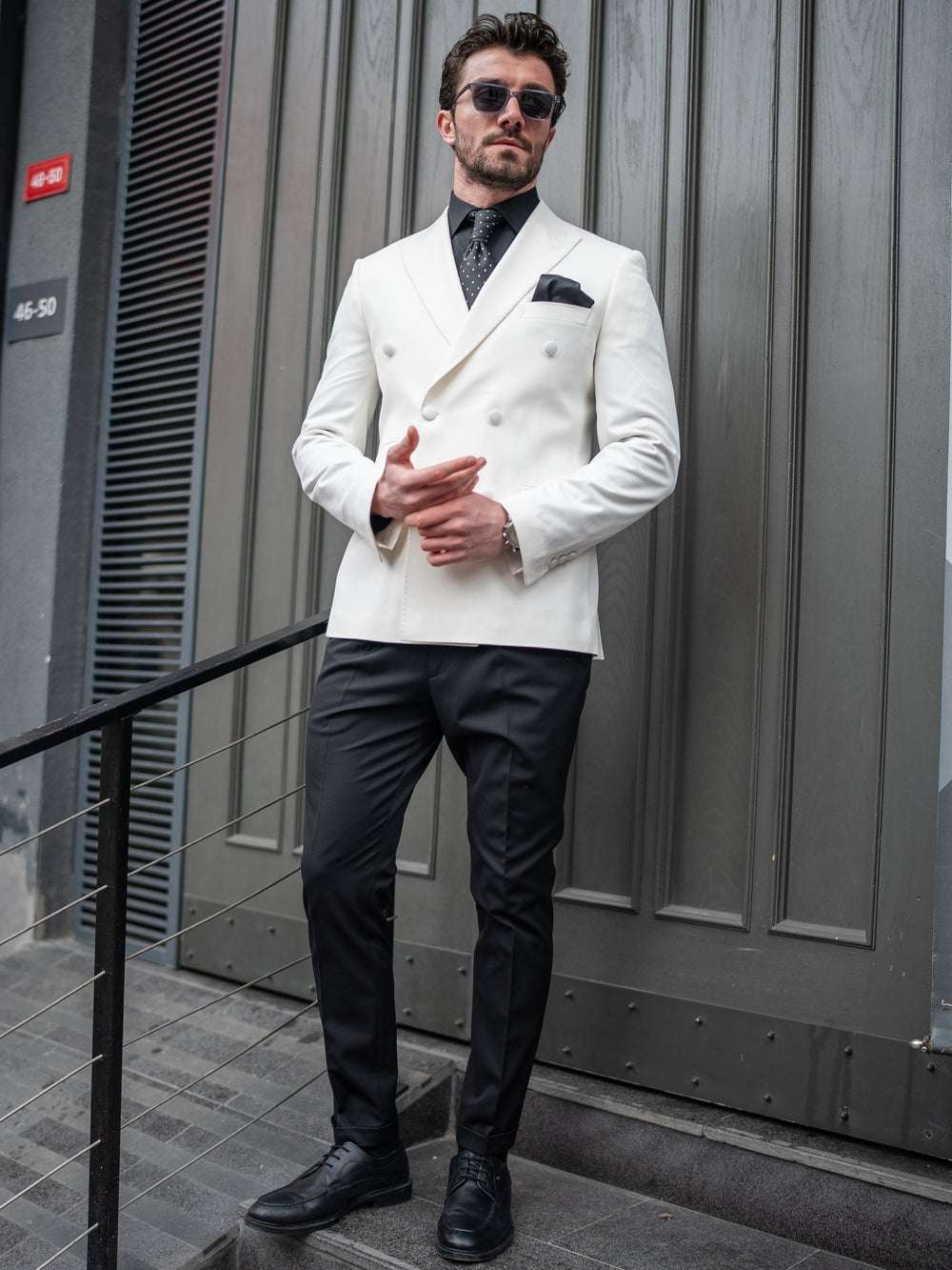 Stylish man in an ivory double breasted tuxedo paired with black pants and sunglasses