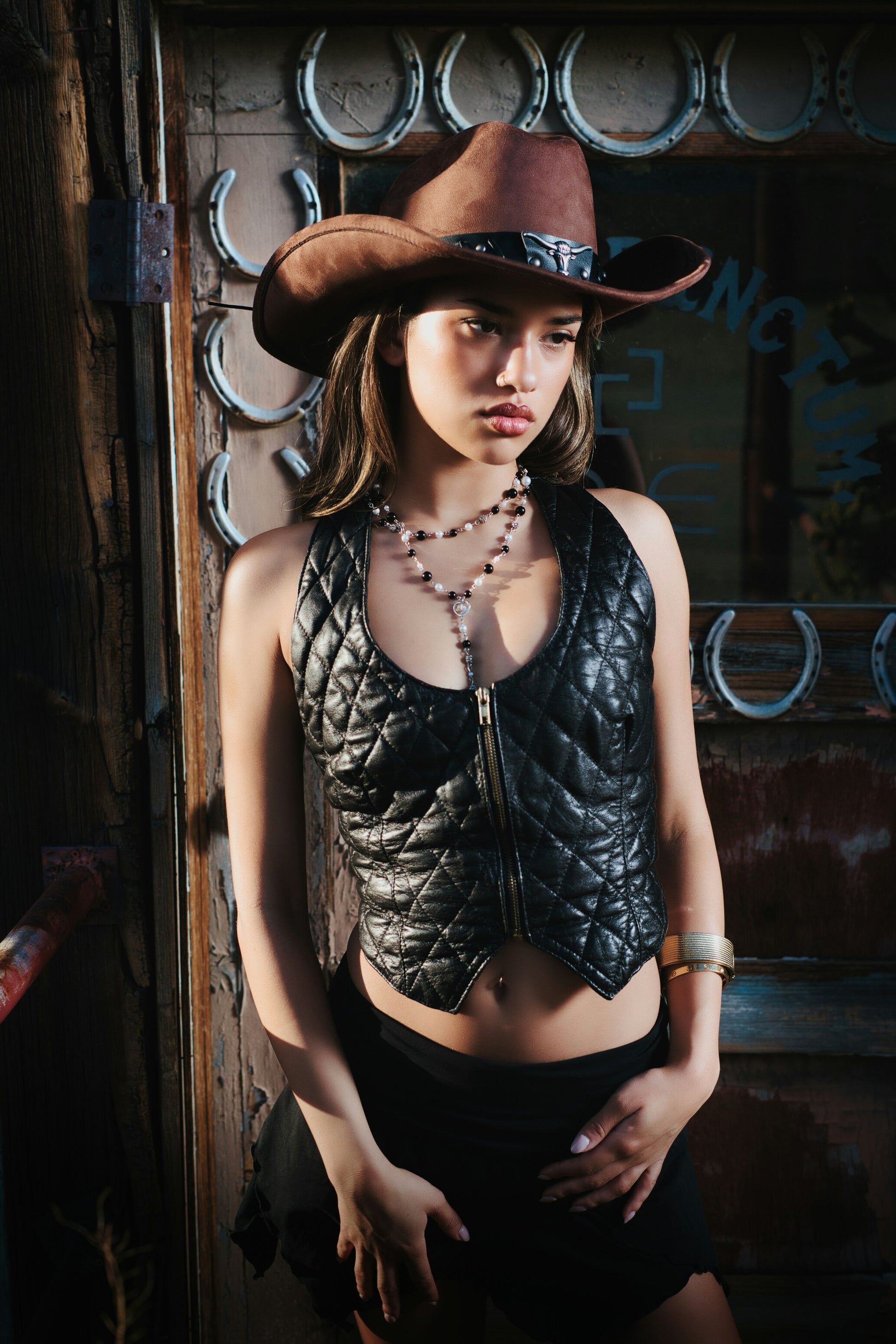 XAYWEAR black leather vest for women styled with a brown cowboy hat and jewelry