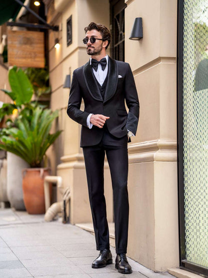 Man wearing a black XAYWEAR three piece suit for men with bow tie and sunglasses outdoors