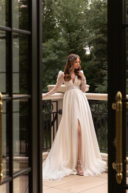 Elegant XAYWEAR bridal gown with long puff sleeves and front slit worn outdoors on balcony