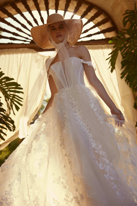 Elegant model showcasing a luxury floral lace gown with delicate detailing and a wide-brimmed hat