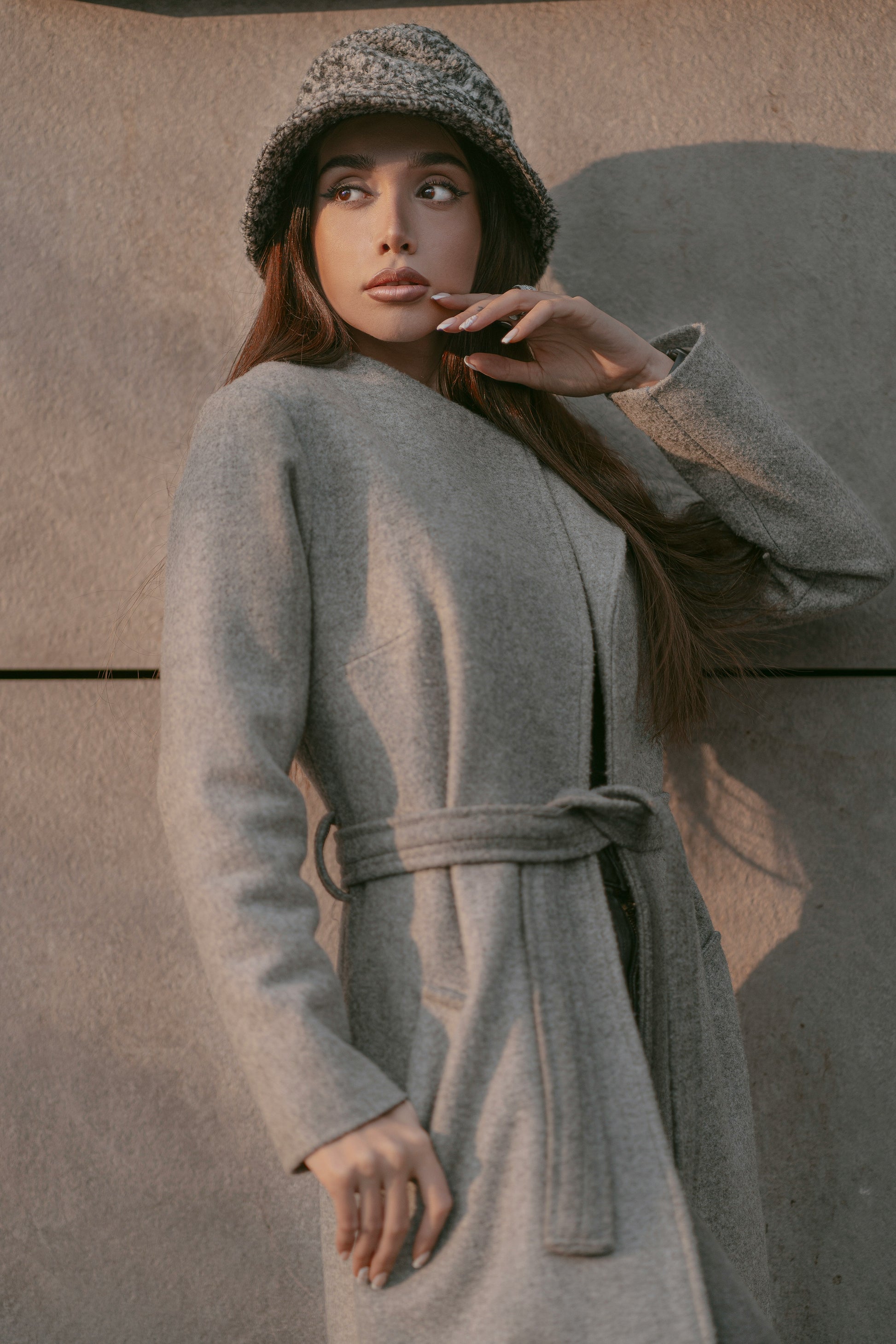 Elegant model wearing a luxury grey coat for women, featuring a belted waist and warm fabric