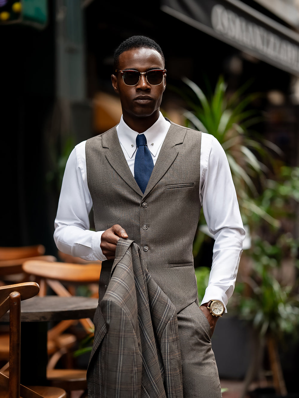 XAYWEAR men suit brown vest and pants with white shirt and blue tie worn by a man holding matching jacket