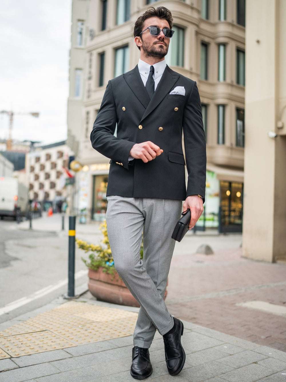 Elegant modern double-breasted blazer in black, styled with gray trousers and accessories for a chic look