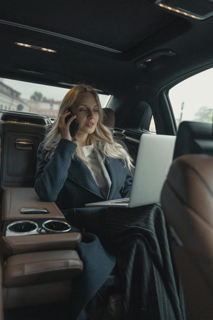 XAYWEAR stylish overcoat worn by a woman in a car while working on a laptop and talking on the phone