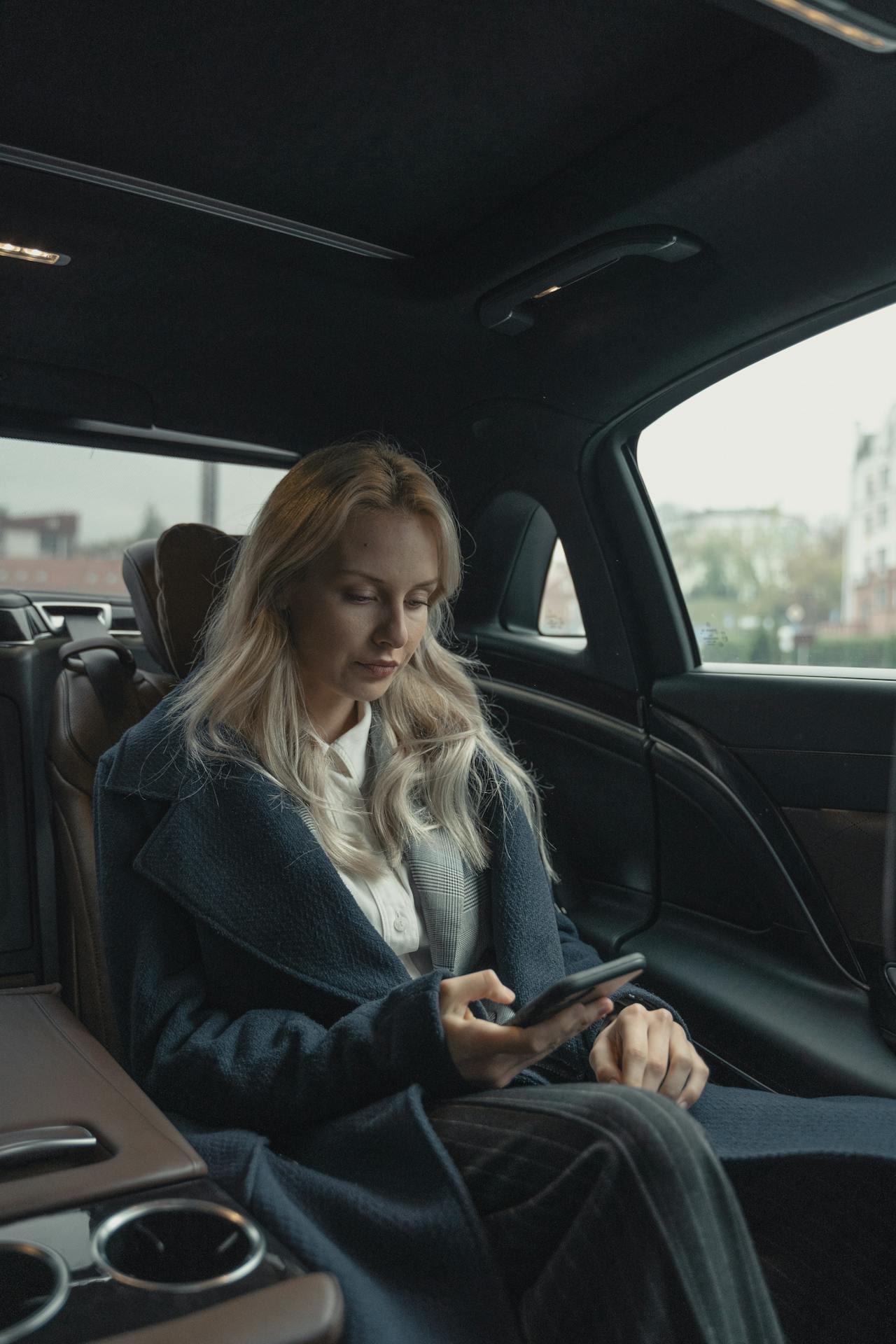 Elegant XAYWEAR overcoat displayed by a woman seated in a luxury car interior