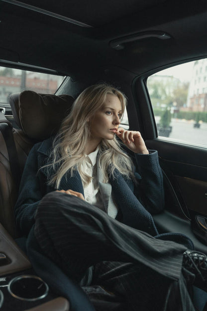 XAYWEAR stylish overcoat worn by a woman sitting in a luxurious car, looking thoughtful