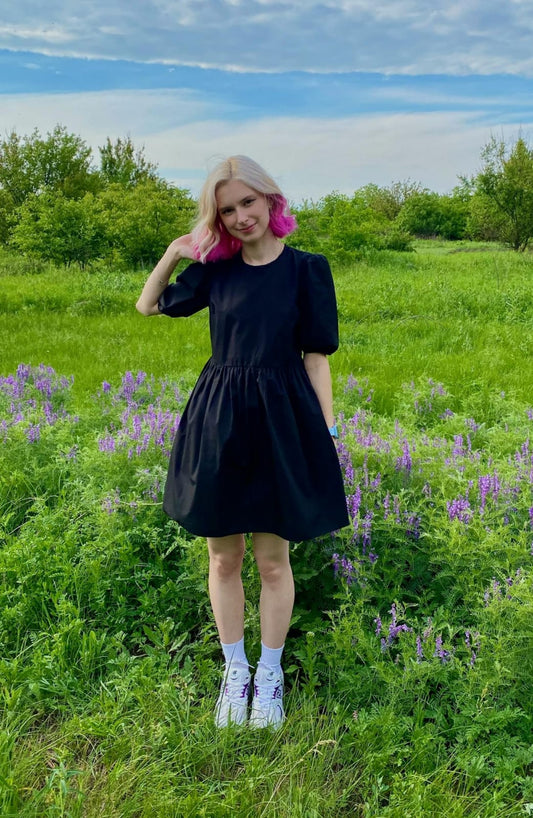 Puff sleeve black dress by XAYWEAR showcased in a green field with flowers