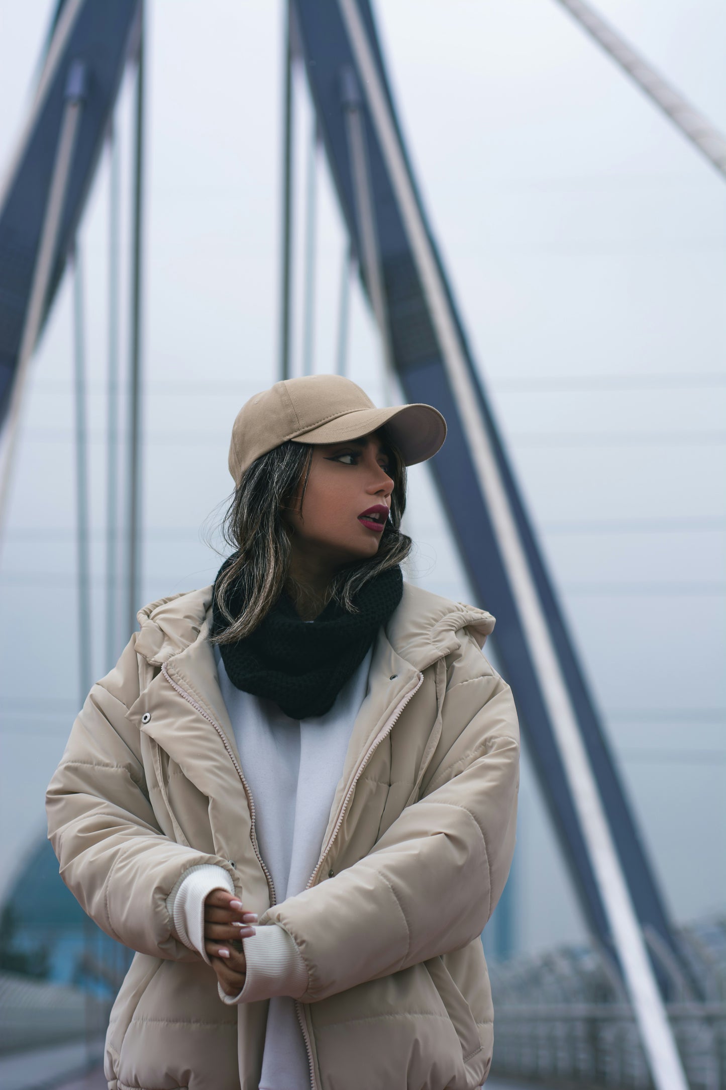 XAYWEAR beige puffer jacket for women with hood worn outdoors with a baseball cap and scarf