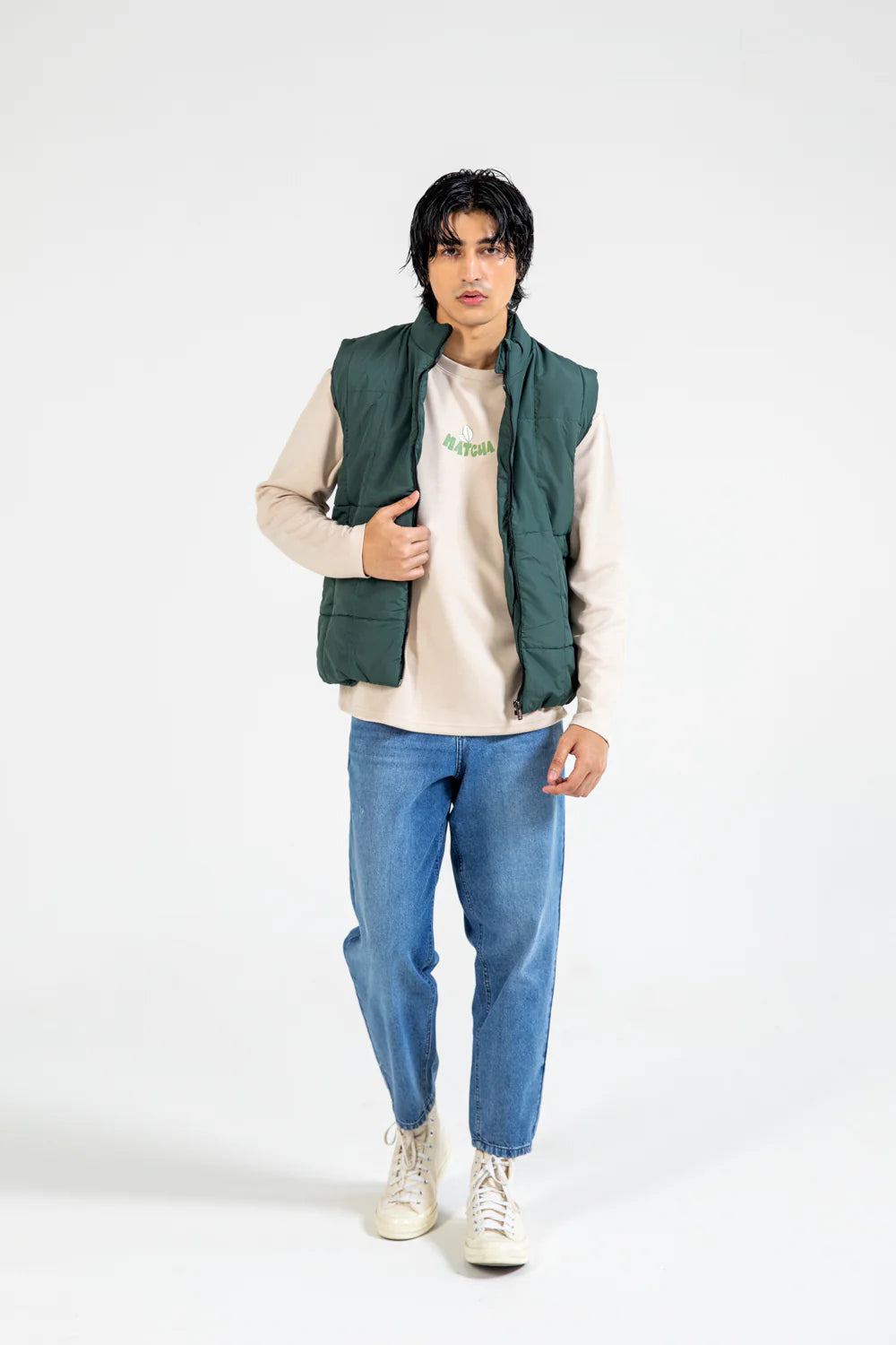 XAYWEAR sleeveless puffer jacket in green paired with a beige sweatshirt and blue jeans