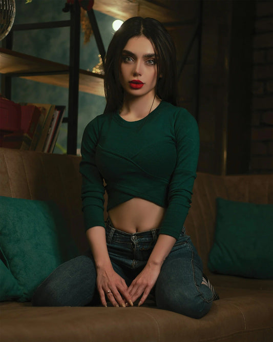 Model wearing a stylish green top for women paired with high-waisted jeans in a cozy setting
