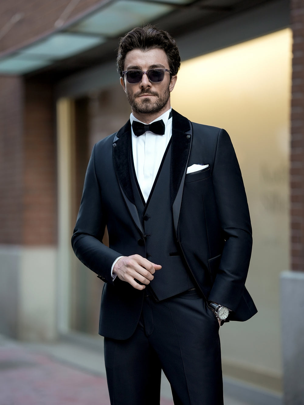 XAYWEAR black three piece suit with satin lapels worn with white dress shirt and black bow tie
