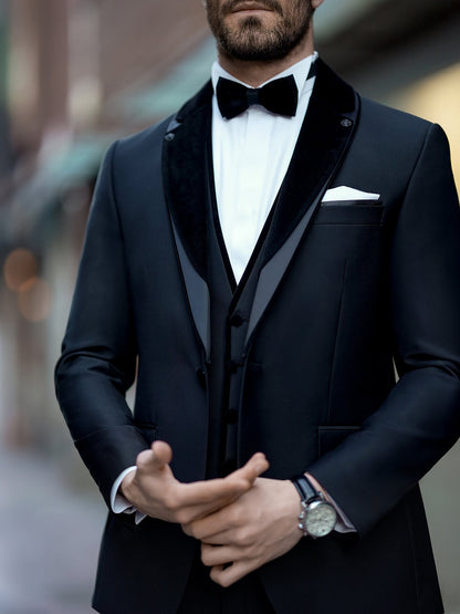 XAYWEAR black three piece suit with velvet lapels and bow tie on a man adjusting his cufflinks