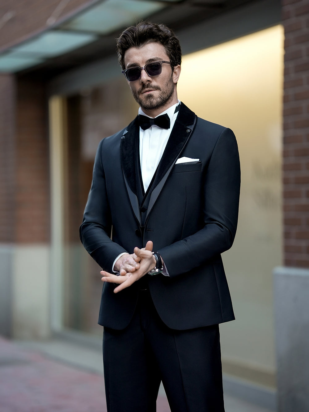 XAYWEAR black three piece suit with velvet lapel and bow tie worn by man with sunglasses