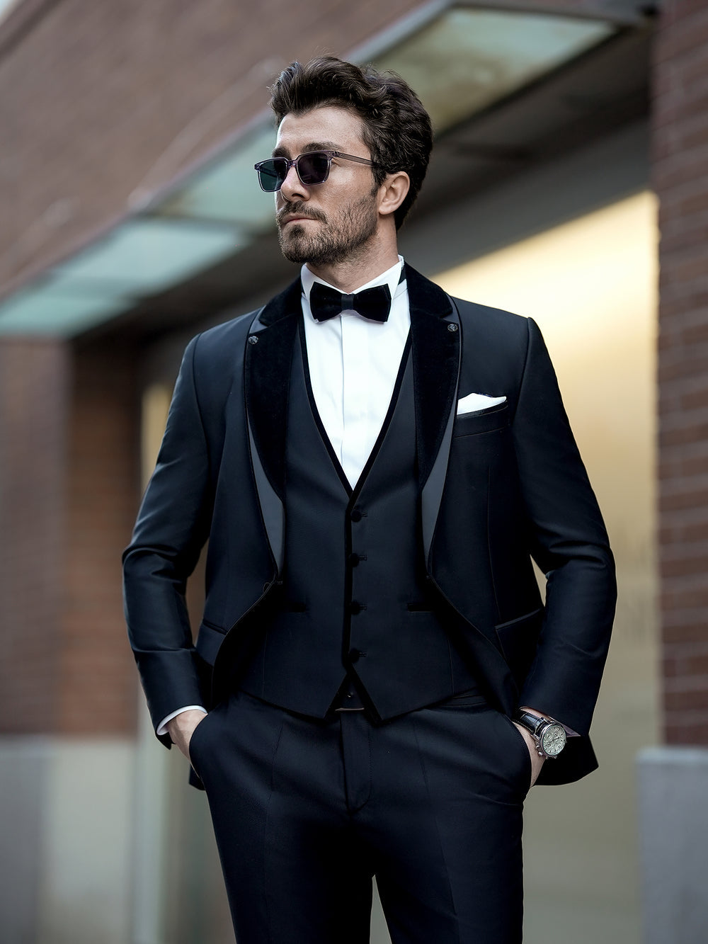 XAYWEAR black three piece suit with bow tie and sunglasses worn by man outdoors