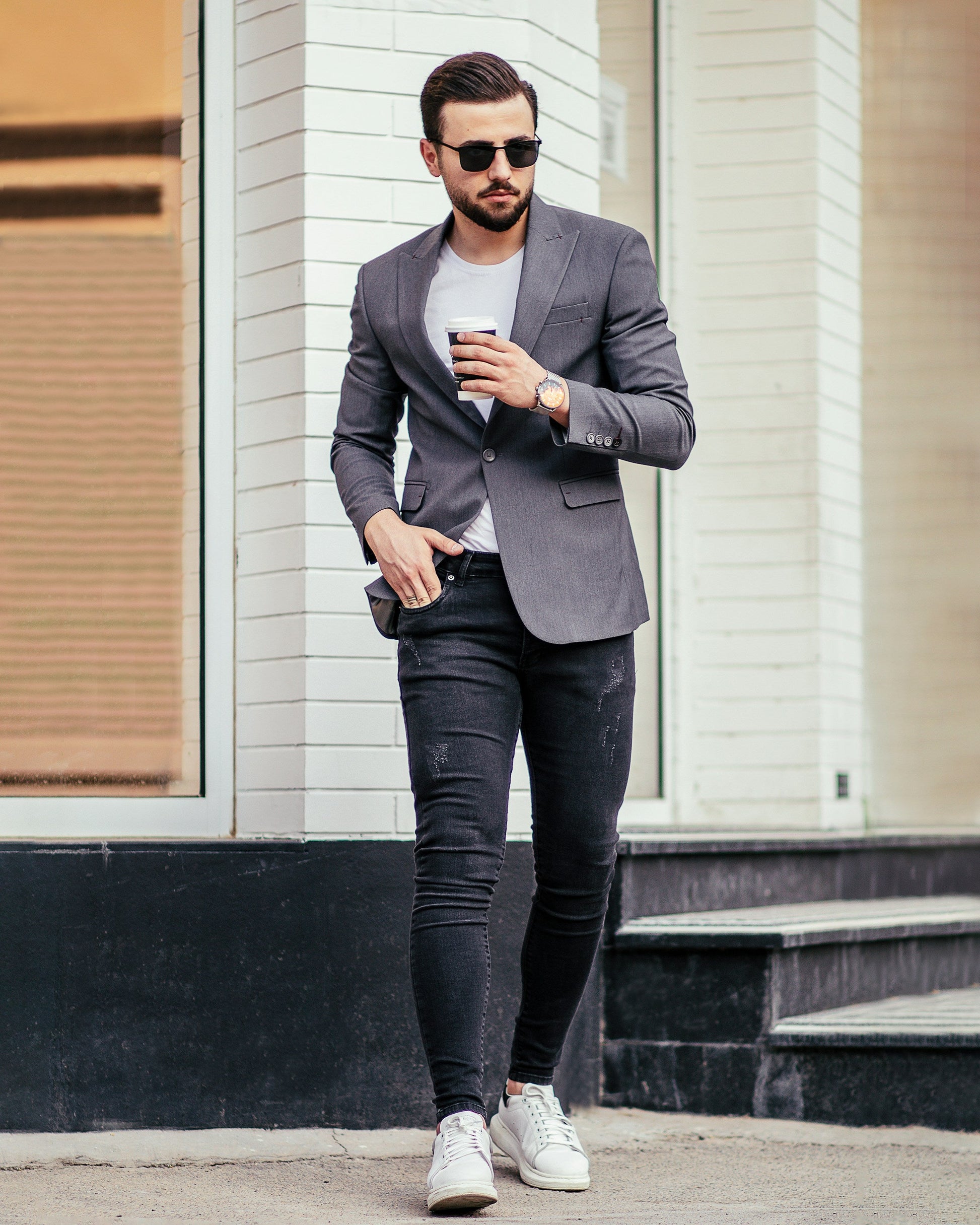 Man wearing Timeless Grey Grace Blazer with casual outfit, holding a coffee cup in urban setting
