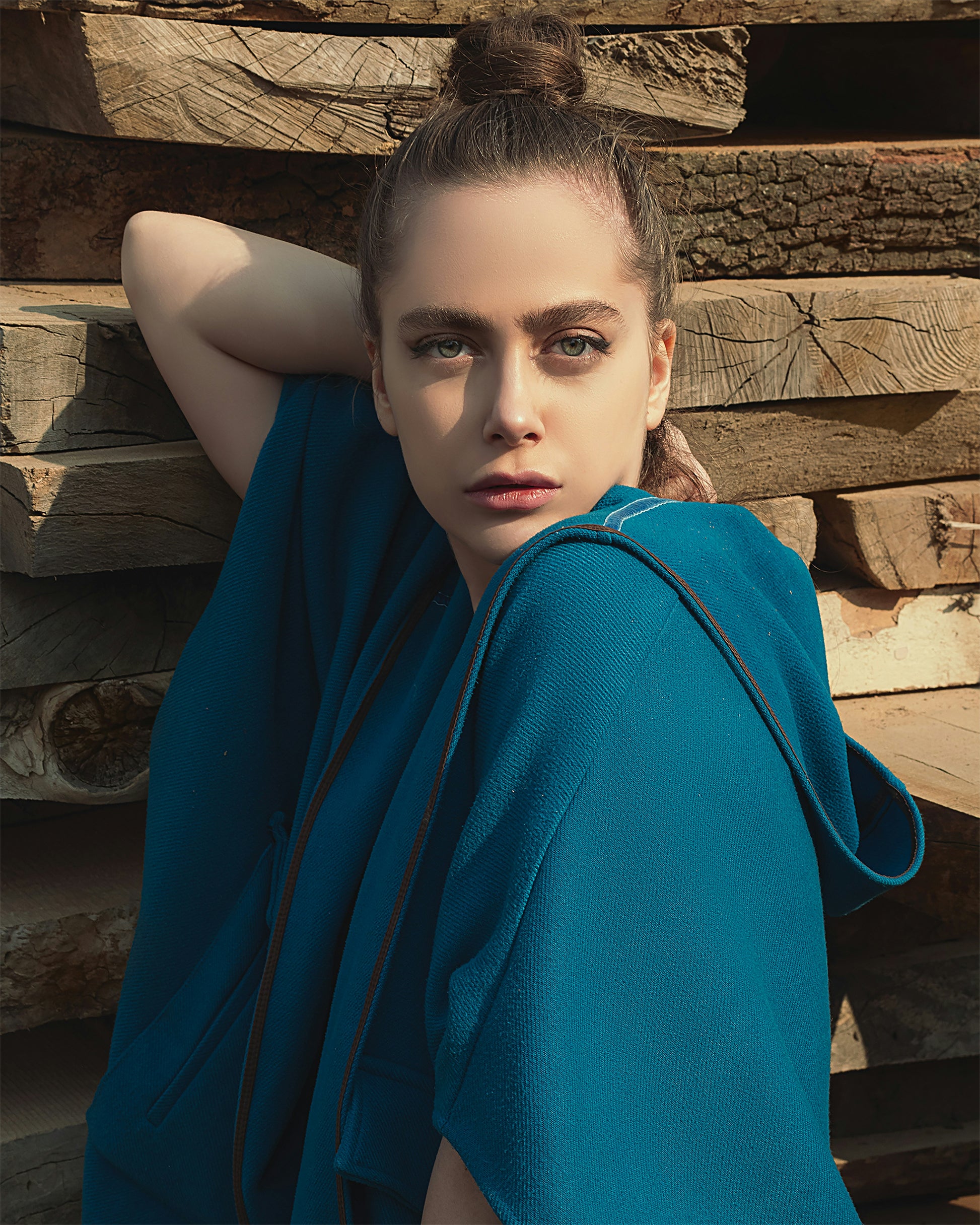 XAYWEAR blue cape jacket for women with hood worn outdoors styled against wooden logs