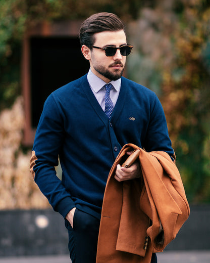 Stylish man holding a brown XAYWEAR coat for men wearing sunglasses and formal attire outdoors