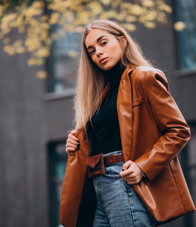 XAYWEAR brown faux leather jacket for women styled with black turtleneck and blue jeans outdoors