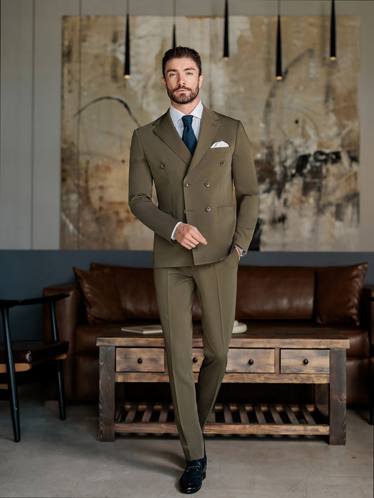 Man wearing an olive double-breasted suit for men by XAYWEAR standing in a modern living room