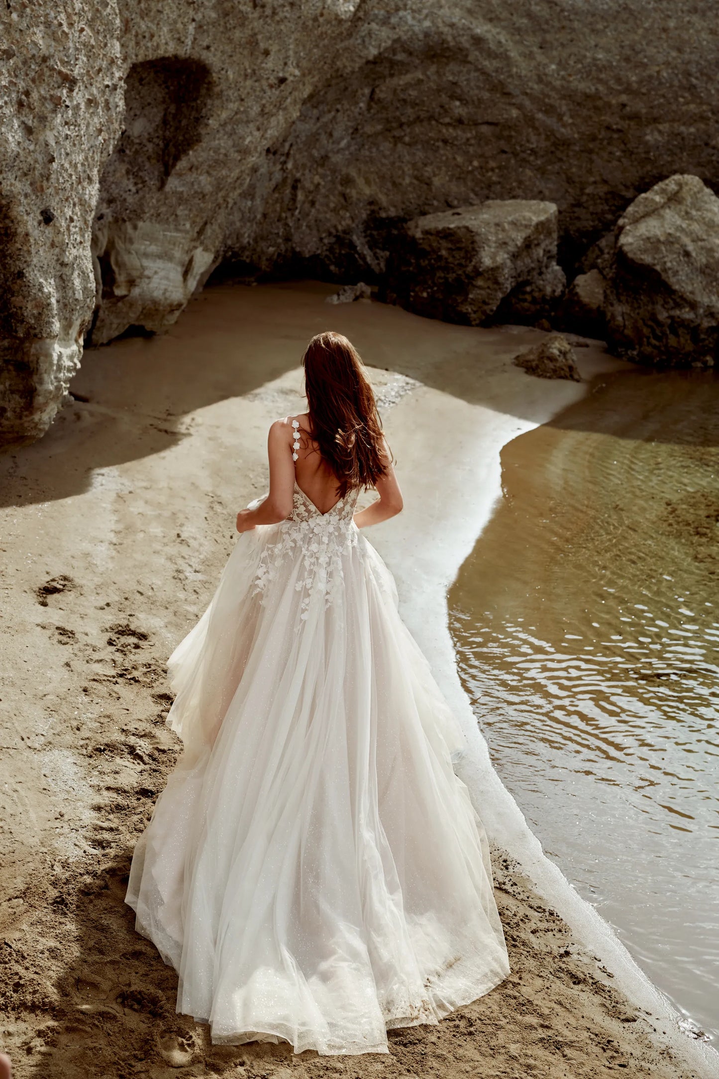 XAYWEAR wedding dress with intricate lace back and flowing tulle skirt on beach near water