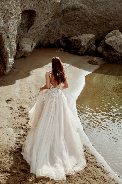 XAYWEAR wedding dress with intricate lace back and flowing tulle skirt on beach near water