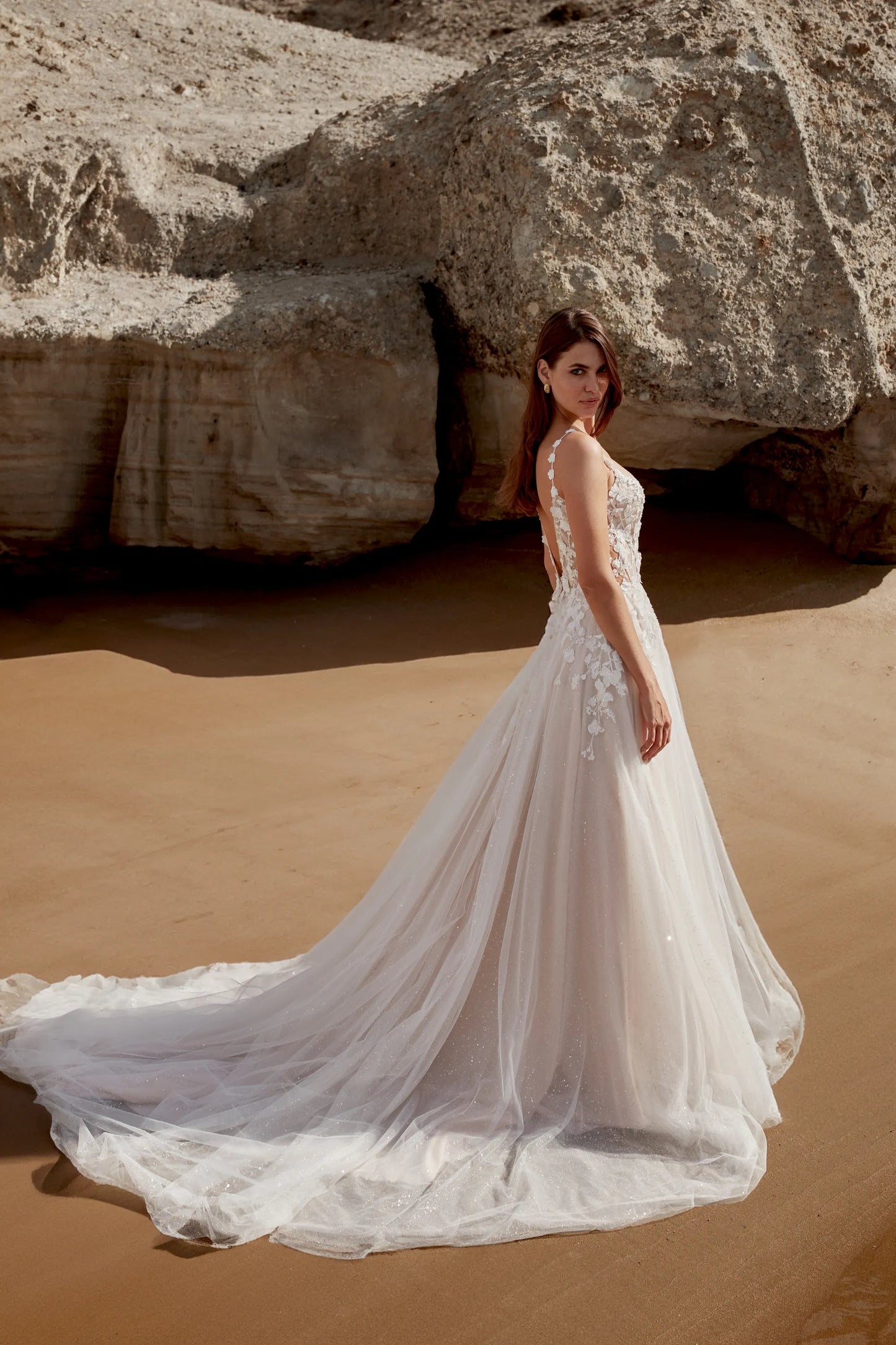 XAYWEAR elegant wedding dress gown with long flowing train and lace details on model at sandy rocky beach