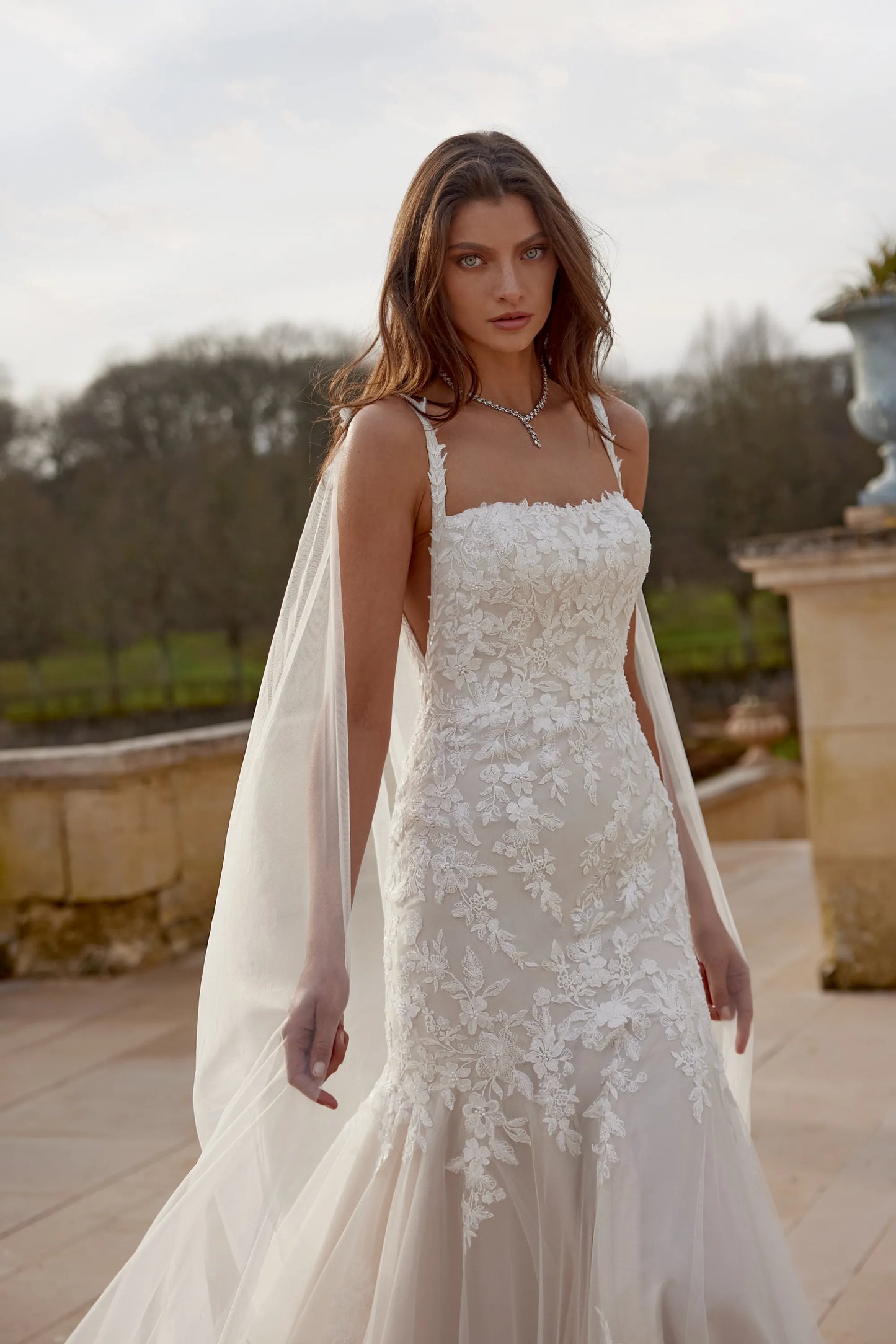 XAYWEAR wedding dress with floral lace detailing and sheer train on model outdoors