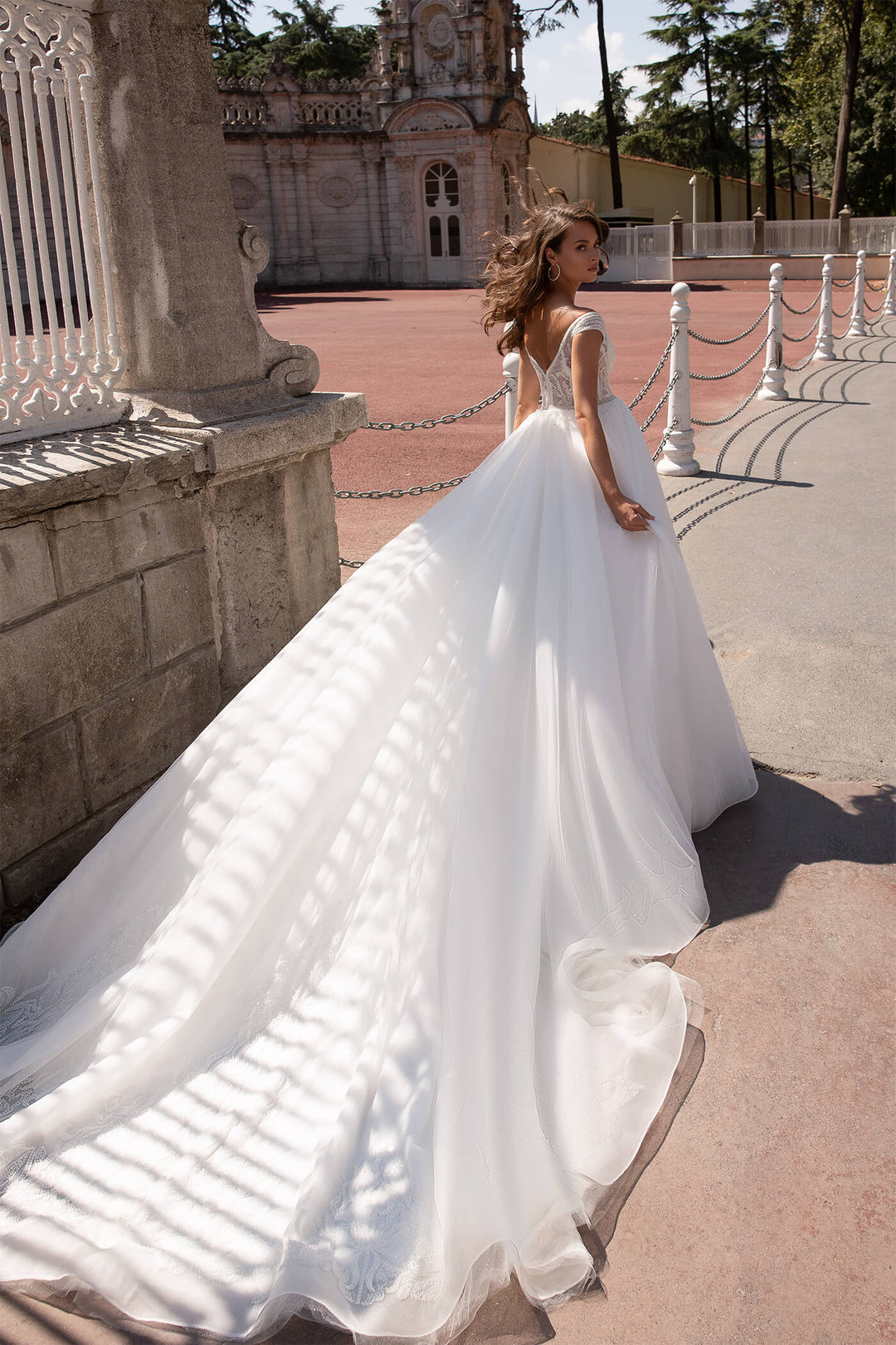 XAYWEAR elegant wedding dress with long flowing train worn outdoors in a historic setting