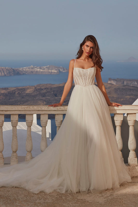 XAYWEAR elegant wedding dress with lace bodice and flowing tulle skirt against scenic coastal background
