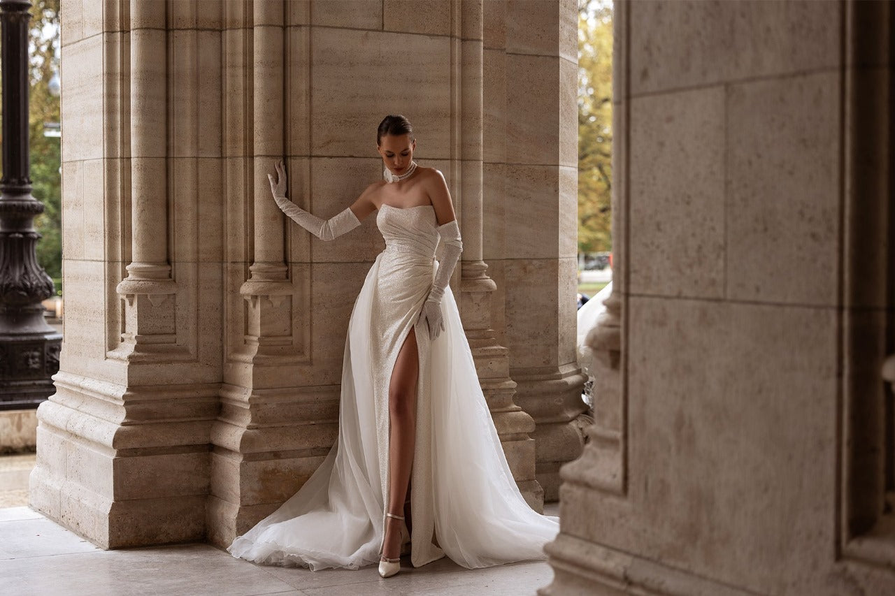 Elegant XAYWEAR wedding gown with a thigh-high slit and long gloves in a classical architectural setting