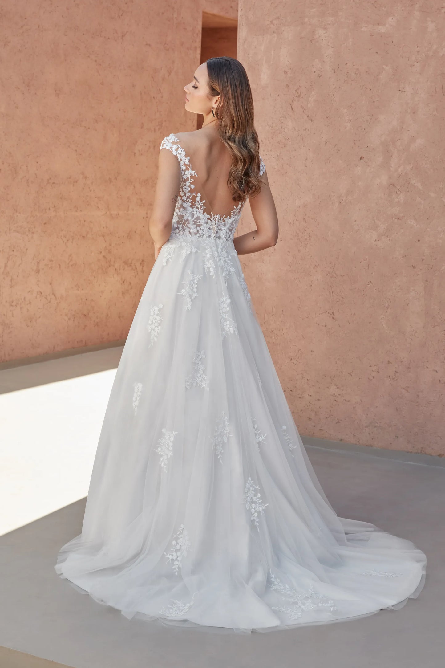 Elegant XAYWEAR wedding white gown with lace details and a flowing train, shown from the back