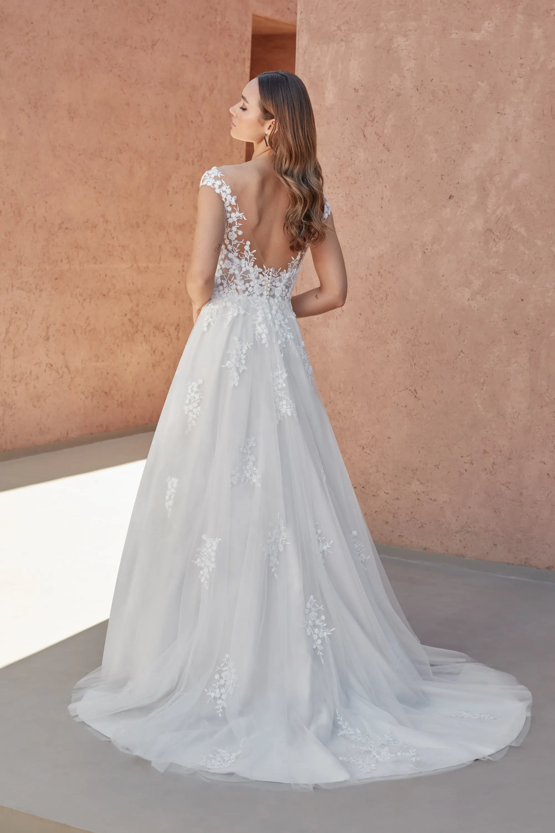 Elegant XAYWEAR wedding white gown with lace details and a flowing train, shown from the back