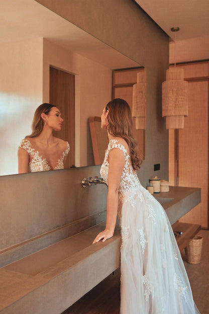 Woman wearing XAYWEAR wedding white gown with lace details leaning on bathroom counter