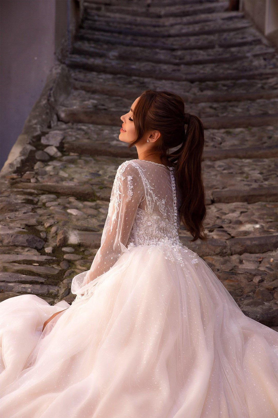 Elegant XAYWEAR white bridal gown with sheer lace sleeves and intricate beadwork on bodice
