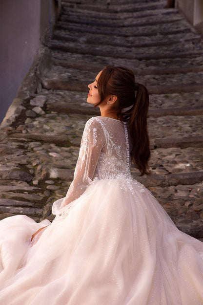Elegant XAYWEAR white bridal gown with sheer lace sleeves and intricate beadwork on bodice