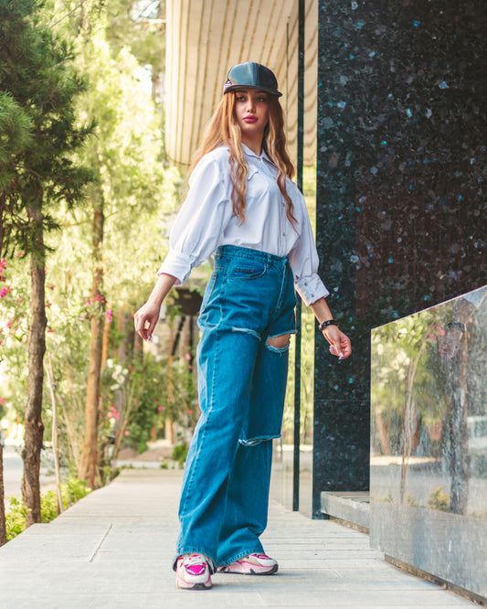 XAYWEAR white shirt for women styled with ripped blue jeans and a black cap outdoors