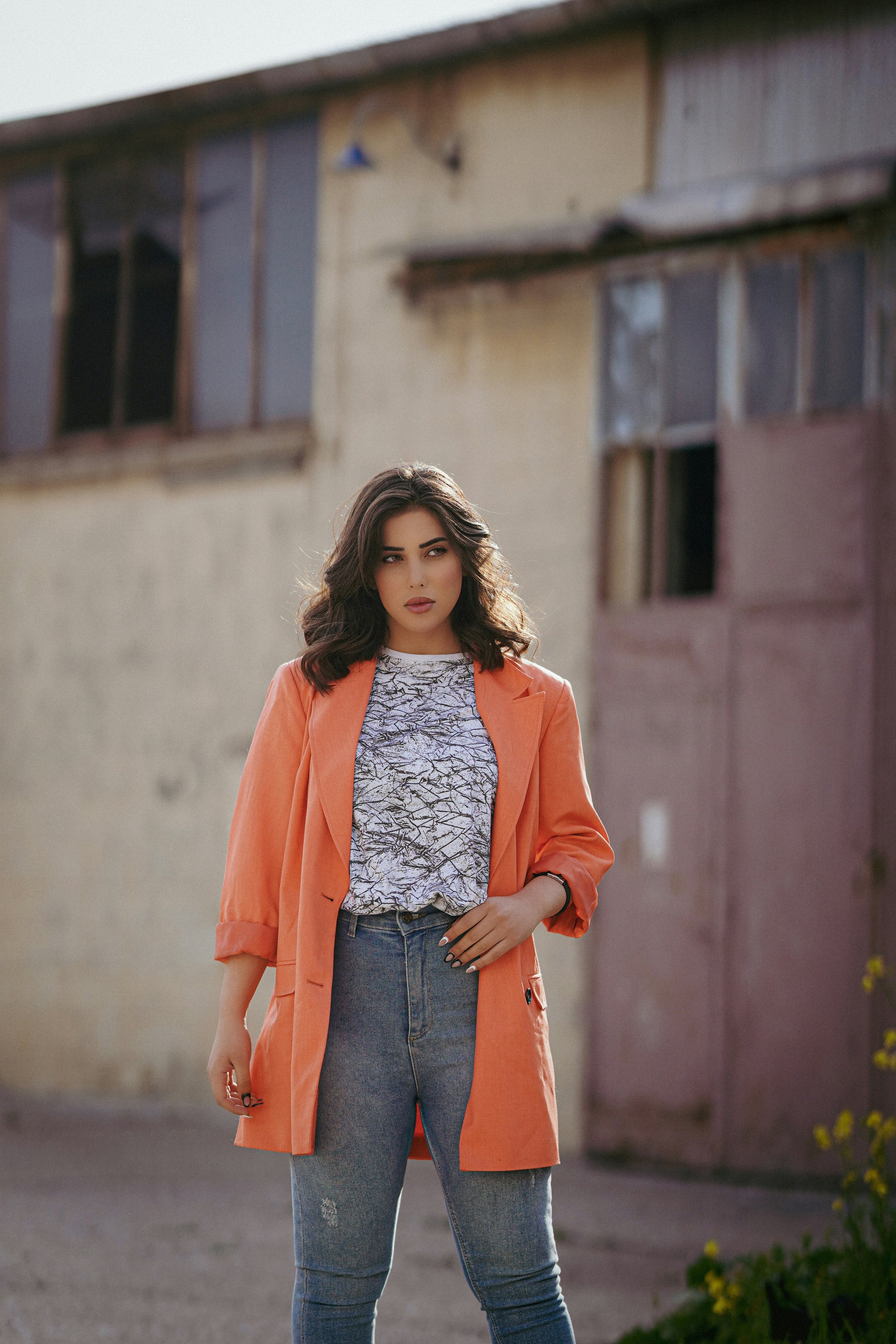 XAYWEAR orange blazer styled as a women coat paired with jeans and patterned top outdoors