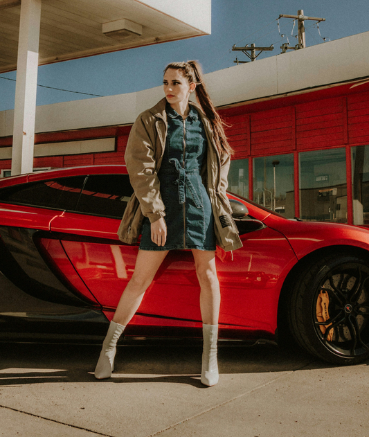 XAYWEAR women denim midi dress styled with a casual jacket and ankle boots standing next to a red sports car
