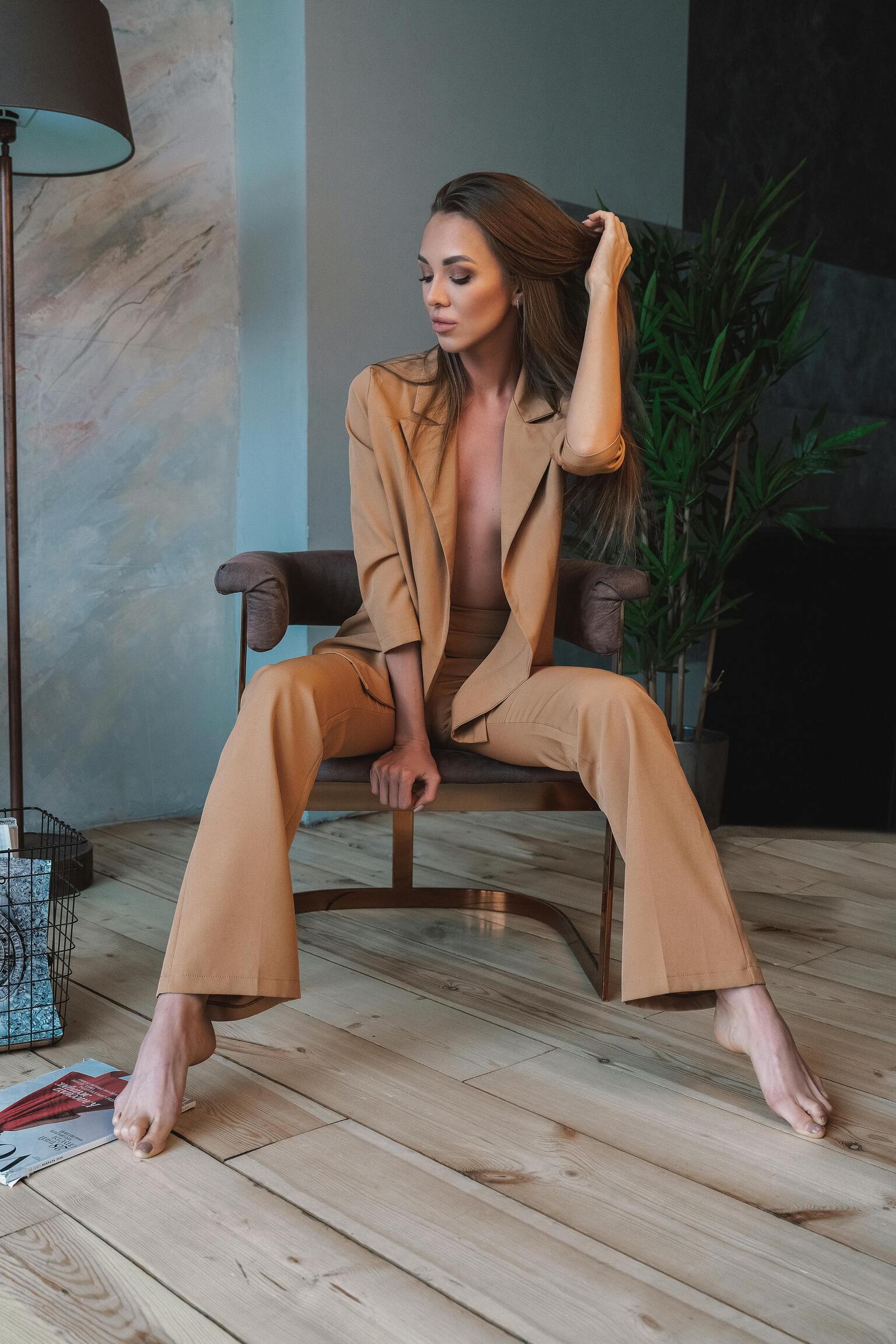 XAYWEAR women formal suit in tan color worn by model seated on chair in modern room