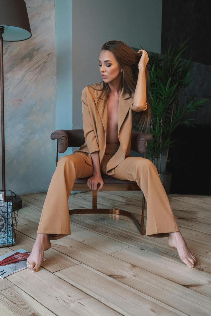 XAYWEAR women formal suit in tan blazer and matching pants seated on a chair indoors