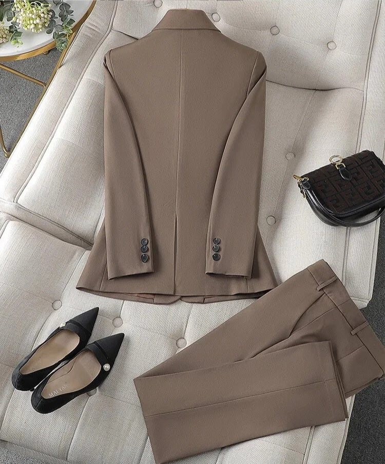 XAYWEAR brown suit for women with blazer and matching pants laid out on a beige sofa with black heels and handbag