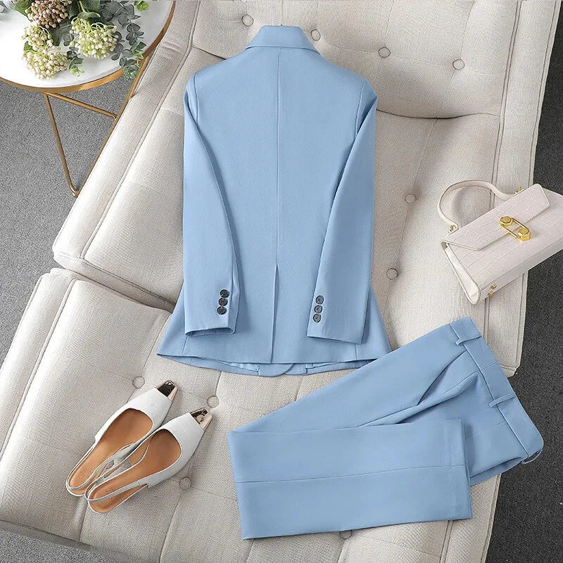 Light blue suit for women from XAYWEAR laid out on a beige sofa with white heels and a beige handbag